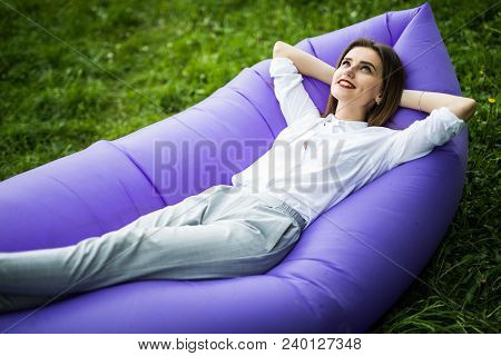 I Love Holydays. Pretty Young Woman Lying On Inflatable Sofa Lamzac While Resting On Grass In Park O