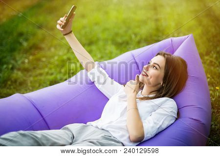 Pretty Young Woman Lying On Inflatable Sofa Lamzac Take Selfie On Phone While Resting On Grass In Pa