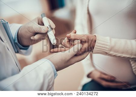 Indian Doctor In White Gown Seeing Patients In Office. Doctor Is Measuring Blood Sugar Of Pregnant W