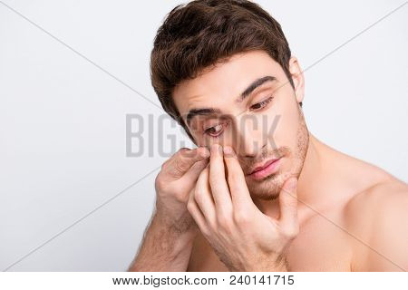 Close Up Portrait Of Young, Attarctive, Muscular Man Putting Contact Lenses In His Eye Over White Ba