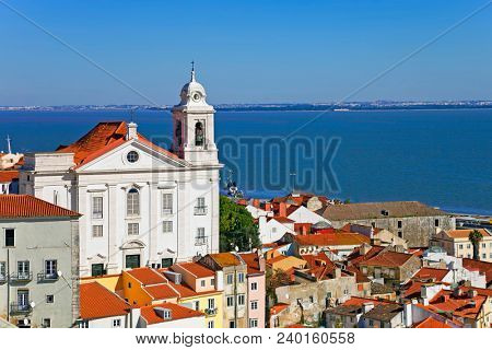 Alfama District with Santo Estevao Church and the Tagus River estuary seen from Miradouro de Santa Luzia viewpoint. Lisbon, Portugal.
