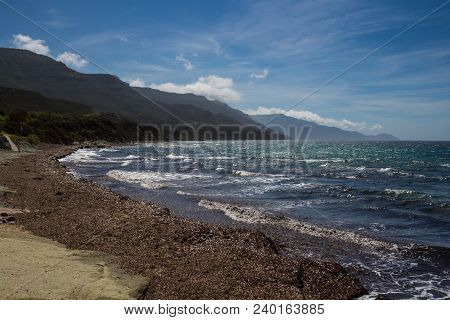Waves Of The Mediterranean Sea At Spiaggia Di Poglina, Surrounded By Mountains. Blue Sky With Clouds