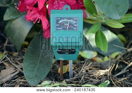 Soil moisture, light and PH meter for small private garden.Rhododendron  flowers as background 