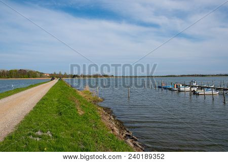 Road Crossing The Sea Towards Danish Island Of Langoe, With Small Fishing Boats In Port