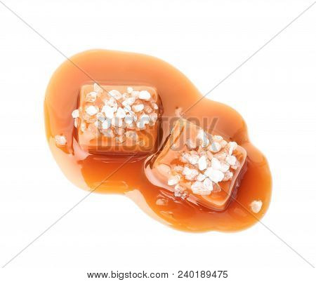 Delicious Candies With Caramel Sauce And Salt On White Background