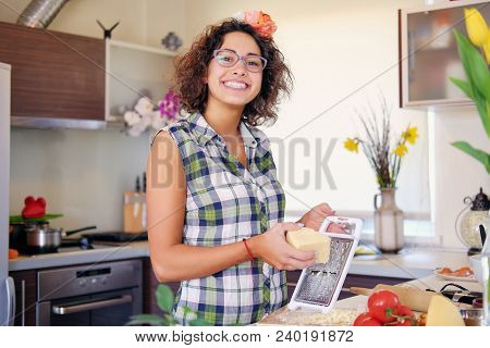 Positive Brunette Female With Curly Hair Makes Salad With Tomatoes And Potato In A Home Kitchen.