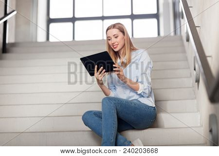 technology, business and corporate concept - happy woman or student with tablet pc computer sitting on stairs
