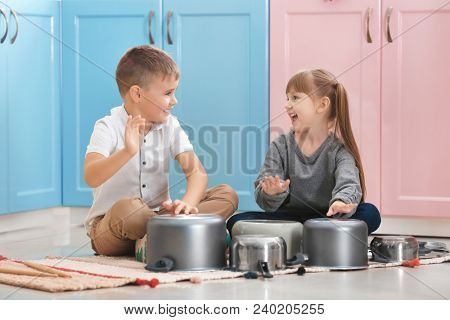 Cute little children playing drums on kitchenware at home