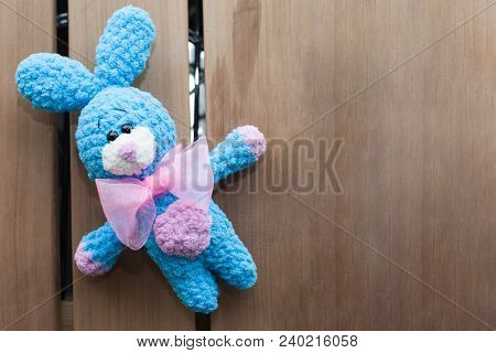 A Small Knitted Blue Rabbit With Pink Bowtie On An Old Wooden Background. Knitted Toy, Handmade. Ami