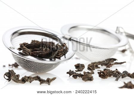 Black Tea, And Tea Strainer With Chain, Isolated On A White Background. A Black Tea And Tea Strainer
