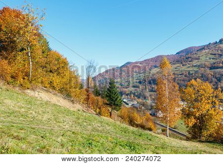 Autumn Carpathian Mountains Landscape With Multicolored Trees On Slope, Railroad And Village Below (