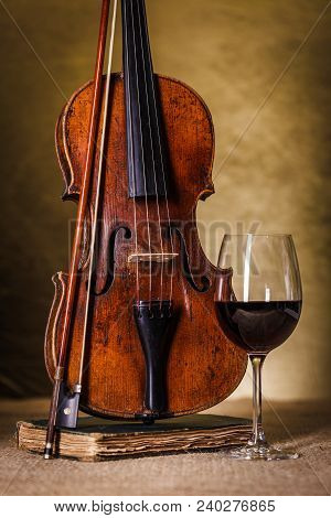 Front View Of A Classical Old Violin With Red Wine Glass