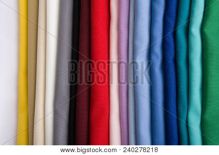 A Pile Of Multicolored Fabrics. Rainbow Fabric Background. Pile Of Bright Folded Fabric