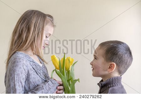 The Little Gentleman Gives The Girl A Bunch Of Flowers. The Little Boy Gives Yellow Tulip