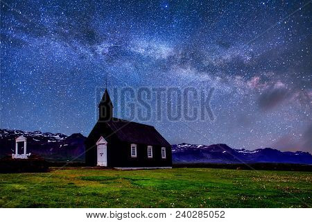 Mountain View Iceland. Fantastic Starry Sky And The Milky Way. Beautiful Black Wooden Church In Budi
