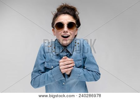 Young Girl In Black Cat Glasses On A Gray Background. Portrait Of A Young Beautiful Girl. Charming G