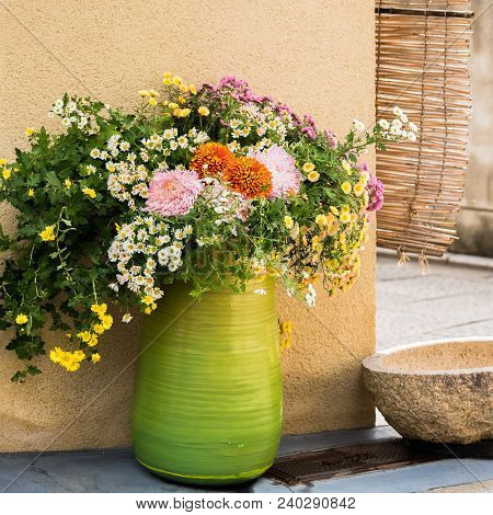 Green Vase With Wild Flowers On A City Street In Kyoto, Japan. Copy Space For Text.