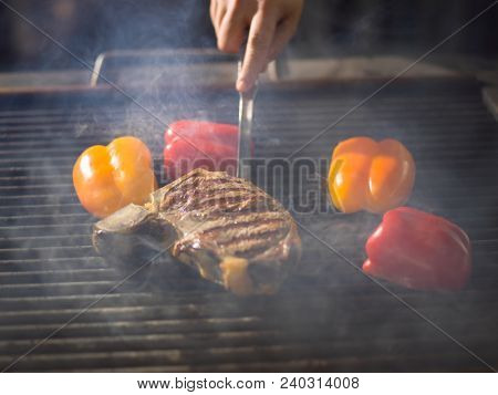 Master chef cooking delicious grilled meat steak with vegetables on a barbecue