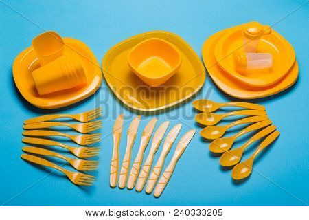 A Set Of Reusable Plastic Tableware Of Yellow Color Is Decomposed On A Blue Background, A Set Of Dis