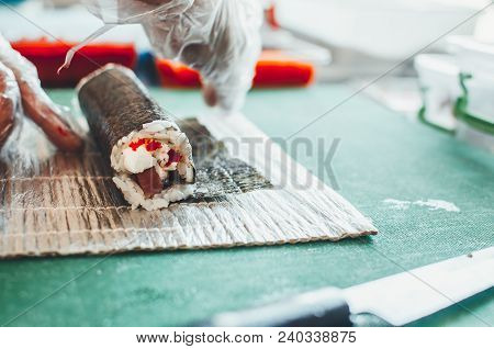 Professional Chef, Chef The Process Of Making Sushi Rolls, Spins Bamboo Mat And Cut Slices