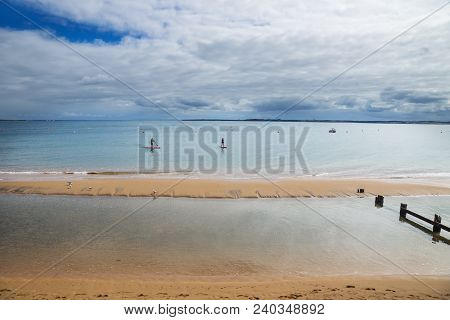 Two Stand Up Paddlers On Surfboards In Blue Water Along Beach In Cowes, Phillip Island, Victoria, Au