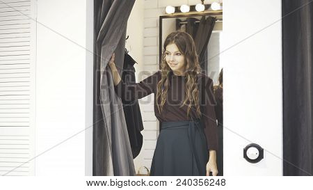 Young Wavy Hair Woman Trying On A Blouse And A Skirt In A Shop Dressing Room. Concept Of Shopping