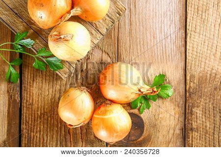 Yellow Onion With Parsley On A Wooden Table