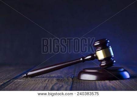 Law Theme. Mallet Of The Judge On Wooden Desk And Violet Background. Place Fort Ext.