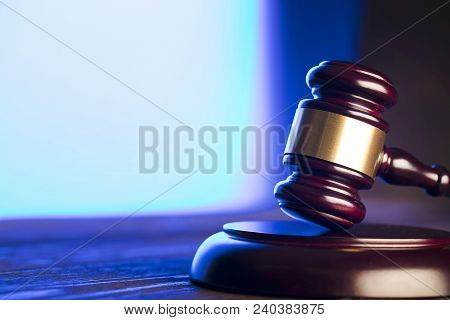 Law theme. Mallet of the judge on wooden desk and blue background. Place for text.