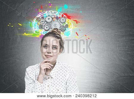 Portrait Of Young Woman Wearing A White Dotted Shirt And Sitting With Her Hand On The Chin. She Is L