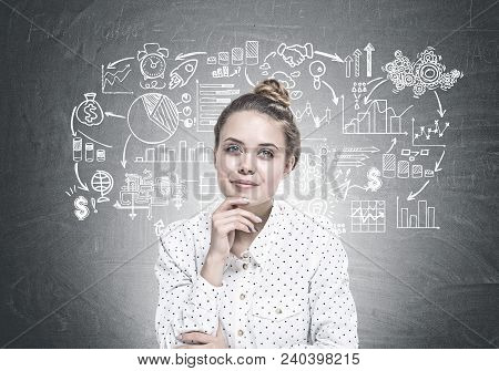 Portrait Of A Young Woman Wearing A White Dotted Shirt And Sitting With Her Hand On The Chin. She Is