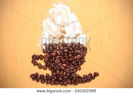 Cappuccino Time. Roasted Coffee Beans Placed In Shape Of Cup And Saucer With Cinnamon White Froth On