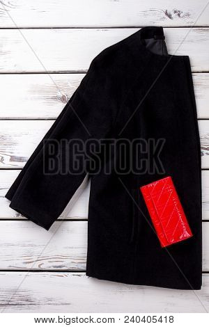 Female Black Coat And Red Purse. Women Topcoat And Red Wallet On White Wooden Background. Ladies Sty