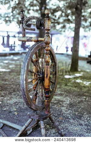 Old Spinning Wheel Stands In The Shade Of The Trees