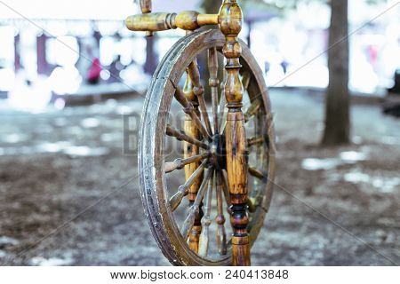 Old Spinning Wheel Stands In The Shade Of The Trees