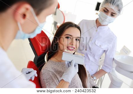 Dentist And Assistant Pick Up The Color Of Teeth For A Young Girl Patient. Teeth Whitening, Tooth Fi