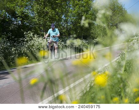 Houten, Netherlands, 9 May 2018: Person On Bicycle Passes Blooming Flowers On Country Road Between U