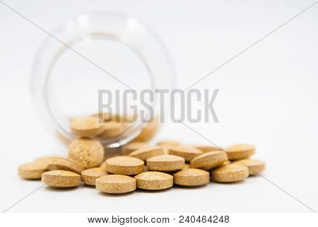 Dropped Container And Yellow Pills On White Background
