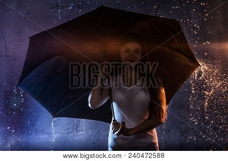 Girl In The White Shirt With Black Umbrella, Water Drops Around And Dark Walls Background Illuminate