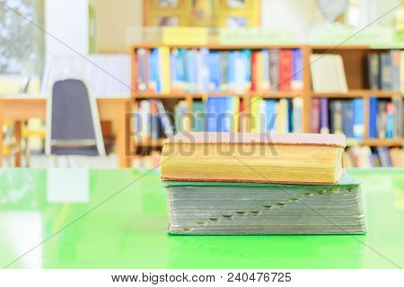 Old Book And Heap Treatise In School Library On Table Green. Blurry Bookshelves Background. Educatio