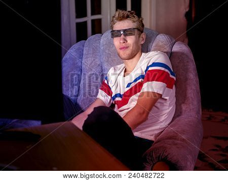 young man sitting on the sofa wathing tv film at home using 3d glasses