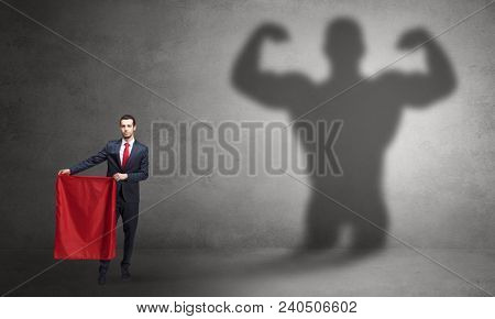 Businessman standing with red cloth on his hand and strong hero shadow on the background