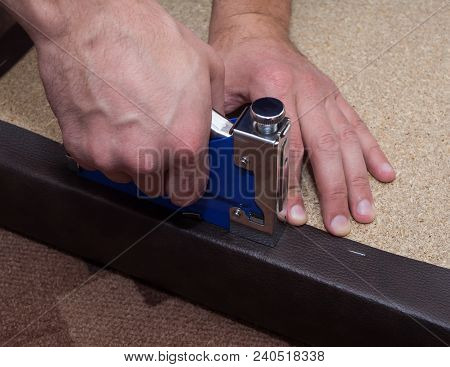 Man Hands Fastening Leather To The Paricle Board Using Stapler And Staples