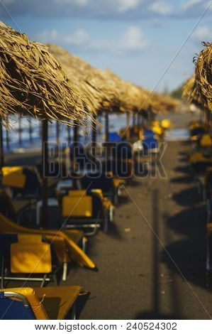 Vacation, Travel, Beach And Beach Umbrellas From The Straw During The Tide. Sea Waves And Empty Sand