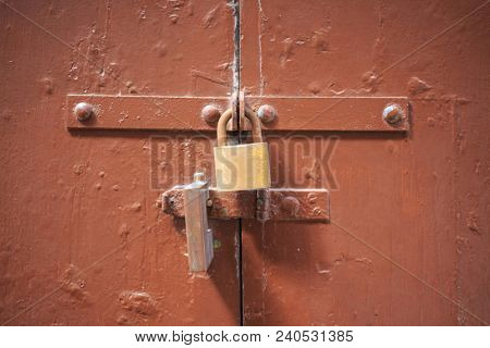 Wooden brown door background locked with two padlocks. Timeworn entrance provides safety and privacy. Close up view with details.