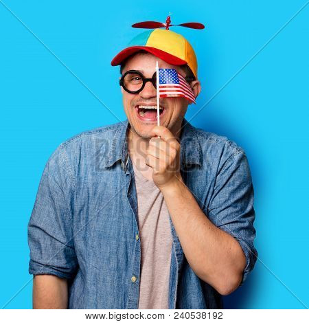 Young Nerd Man With Noob Hat Holding An American Flag On Blue Background