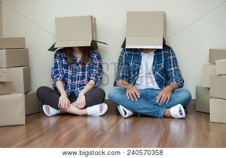 Funny Couple Move With Empty Cardboard Boxes On Their Heads Sitting On Floor After At New Home