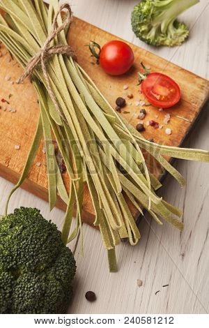 Raw Handmade Green Tagliatelle With Spinach Juice, Broccolli, Tomatoes And Spices On White Wooden Ta