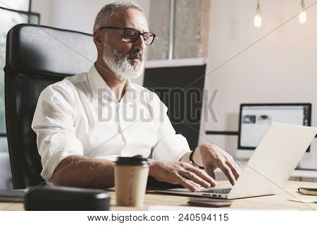 Succes And Confidental Adult Businessman Using Mobile Laptop Computer While Working At The Wooden Ta