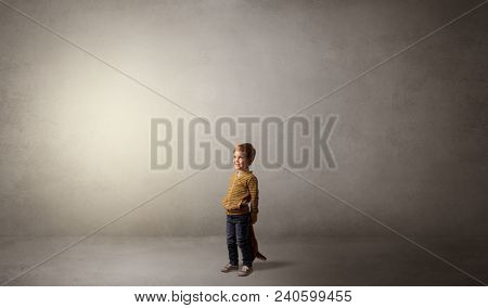 Little waggish kid staying alone in a big empty room with his plush